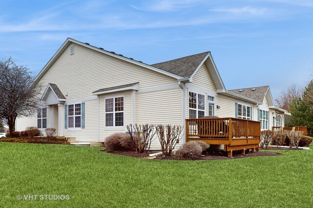 view of property exterior with a shingled roof, a lawn, and a wooden deck