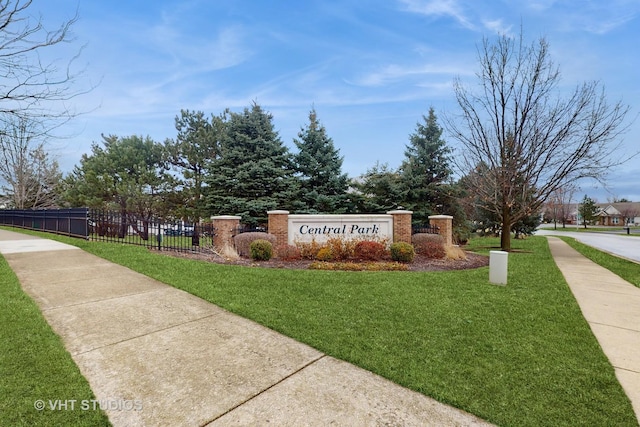 community sign with fence and a lawn