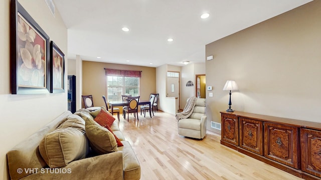 living room with light wood-type flooring, visible vents, and recessed lighting