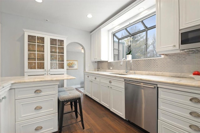 kitchen with stainless steel appliances, tasteful backsplash, a sink, and white cabinets