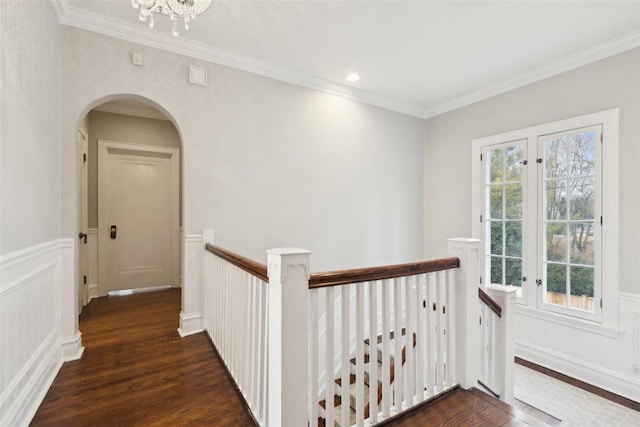 hallway featuring arched walkways, dark wood-type flooring, an upstairs landing, and a healthy amount of sunlight