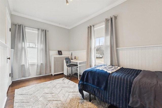 bedroom featuring radiator, wainscoting, crown molding, and wood finished floors