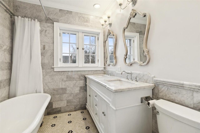 bathroom with toilet, a soaking tub, ornamental molding, a sink, and tile walls