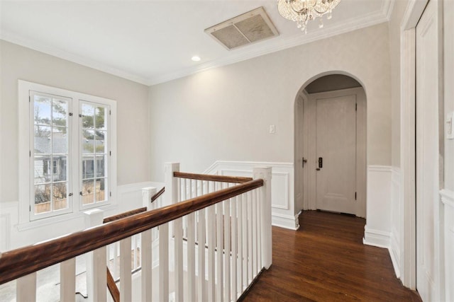 hall with a wainscoted wall, arched walkways, and dark wood-style flooring