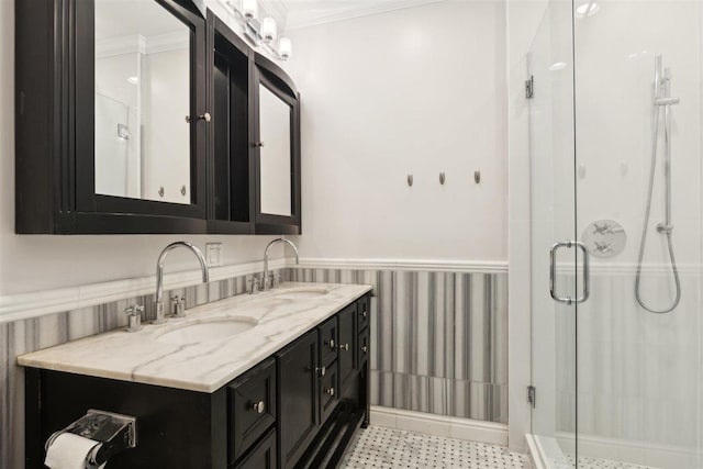 full bathroom featuring ornamental molding, wainscoting, a sink, and a shower stall