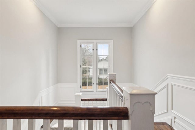 staircase featuring ornamental molding, wainscoting, and a decorative wall