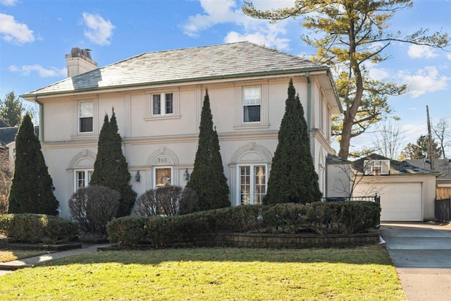 view of front of house featuring a chimney, an outbuilding, a high end roof, a front lawn, and stucco siding