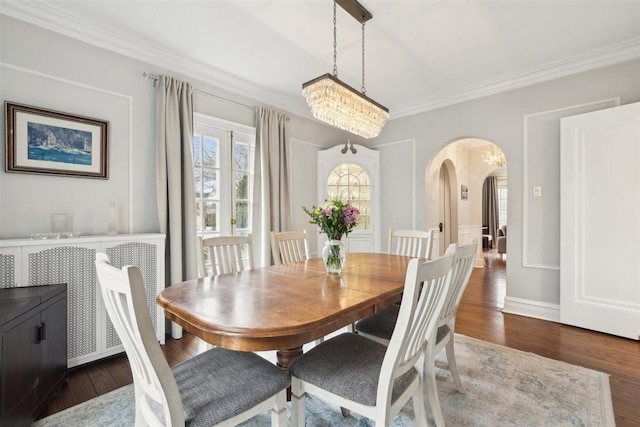 dining area featuring dark wood-style floors, arched walkways, a notable chandelier, and ornamental molding