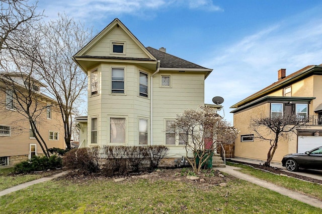 view of front facade with a shingled roof and a front yard