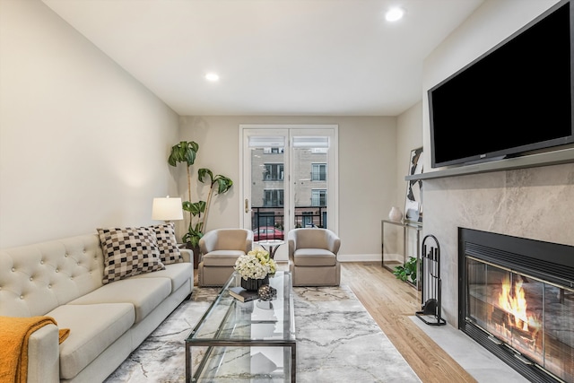 living area featuring light wood-style floors, a fireplace with flush hearth, baseboards, and recessed lighting