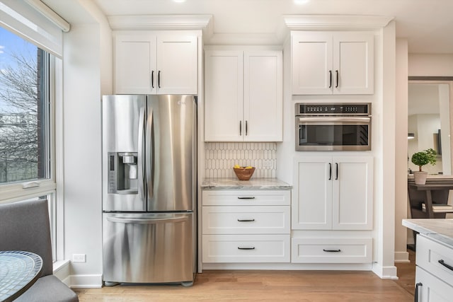 kitchen featuring stainless steel appliances, light stone counters, white cabinets, and light wood-style floors