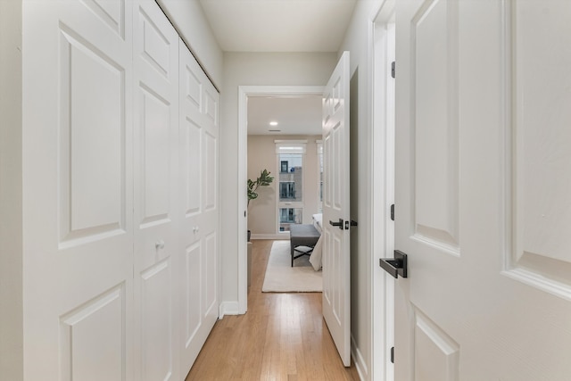 hallway with light wood-type flooring and baseboards