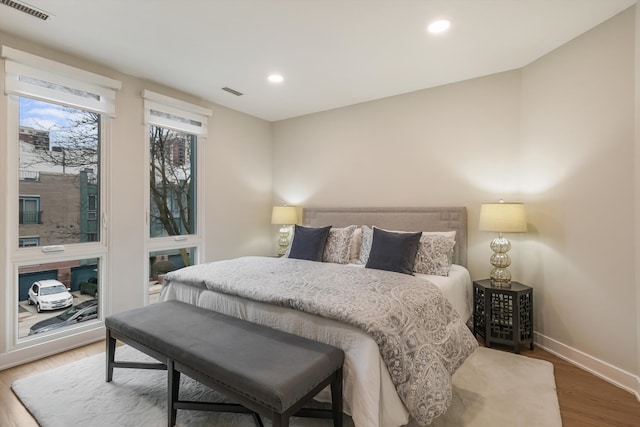 bedroom featuring baseboards, visible vents, wood finished floors, and recessed lighting