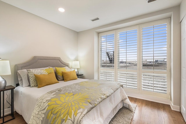 bedroom featuring baseboards, visible vents, multiple windows, and wood finished floors