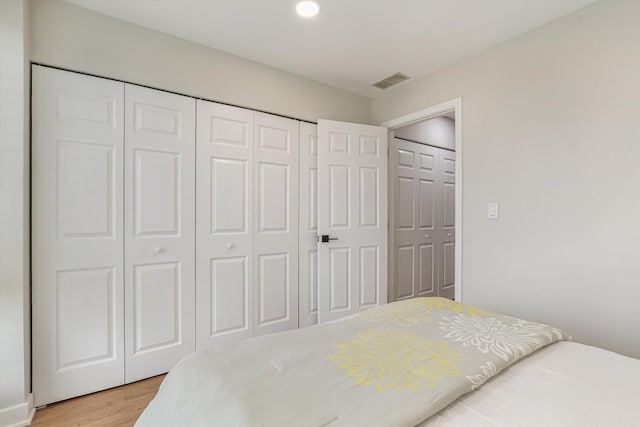 bedroom featuring a closet, visible vents, and light wood finished floors