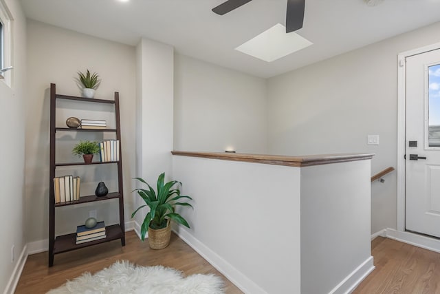 bar featuring a skylight, baseboards, and wood finished floors