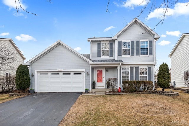 traditional home featuring aphalt driveway, an attached garage, and a front yard