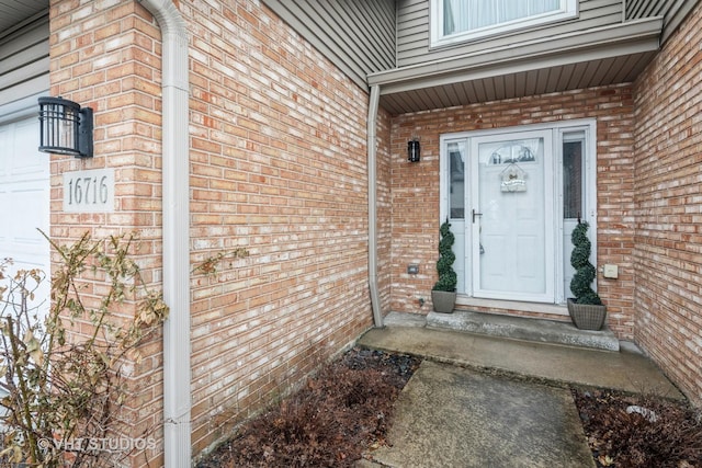 property entrance with a garage and brick siding