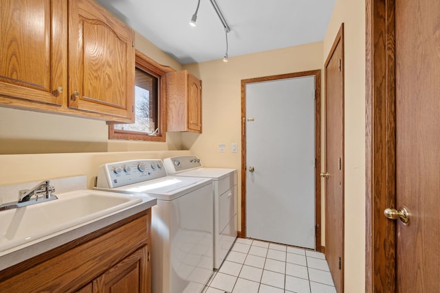 washroom featuring cabinet space, light tile patterned floors, track lighting, washing machine and clothes dryer, and a sink