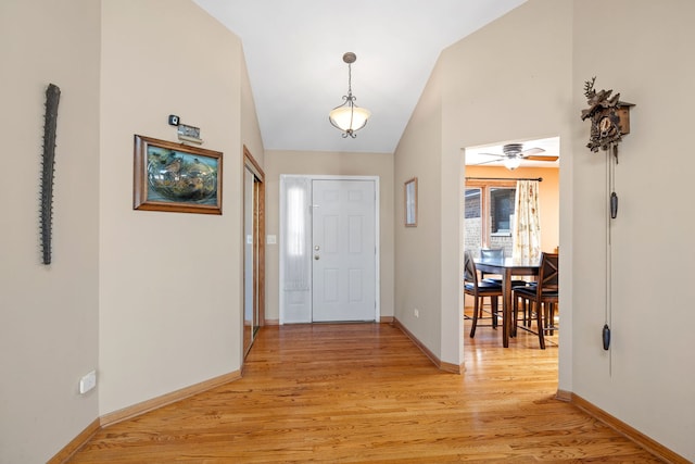 foyer with light wood-type flooring, high vaulted ceiling, and baseboards