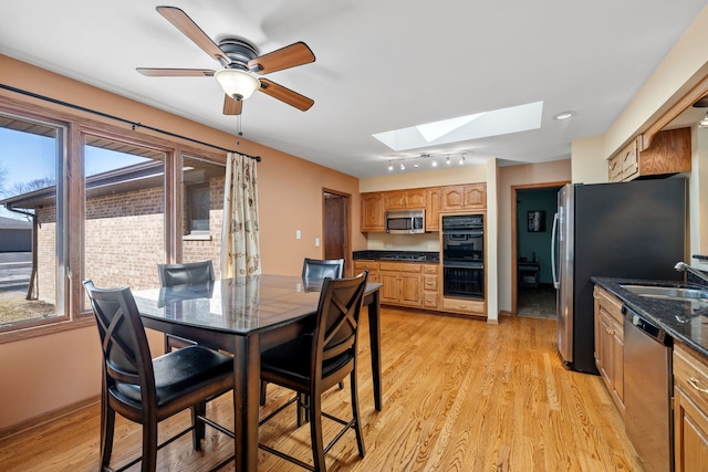 dining room with light wood finished floors, plenty of natural light, and a skylight