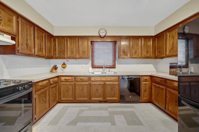 kitchen featuring a sink, brown cabinets, black appliances, and light countertops