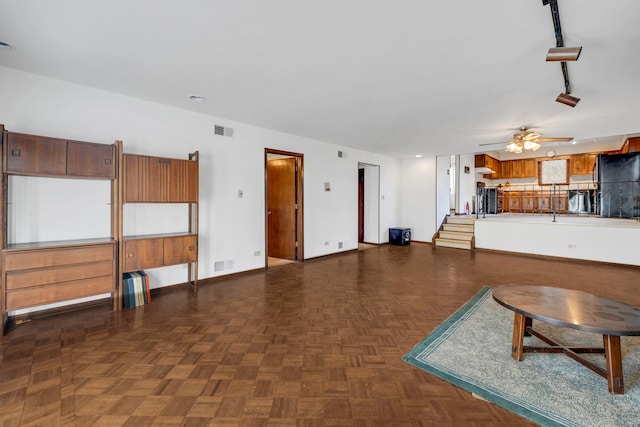 unfurnished living room with track lighting, a ceiling fan, visible vents, and baseboards