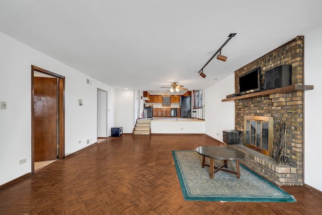 unfurnished living room with a fireplace, a ceiling fan, rail lighting, and baseboards