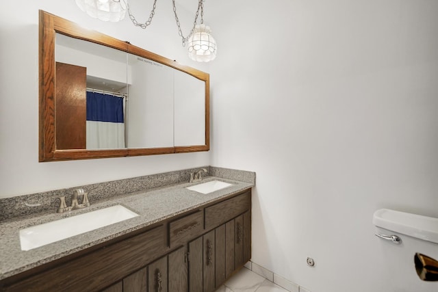 bathroom with double vanity, toilet, marble finish floor, and a sink