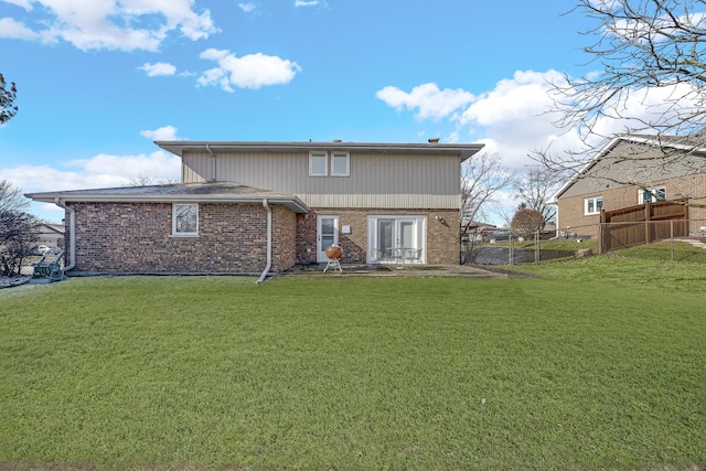 back of house featuring a yard, brick siding, and fence