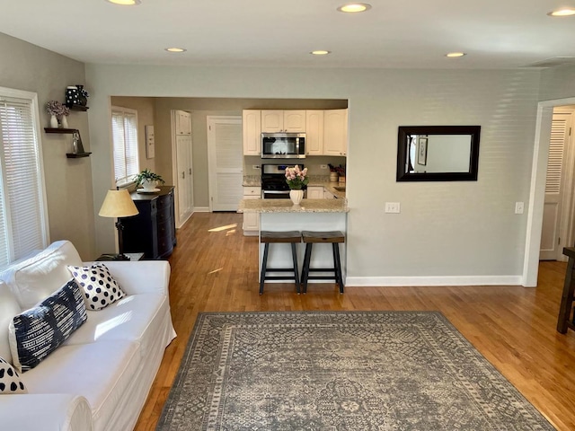 kitchen with a peninsula, appliances with stainless steel finishes, white cabinets, and dark wood-style flooring