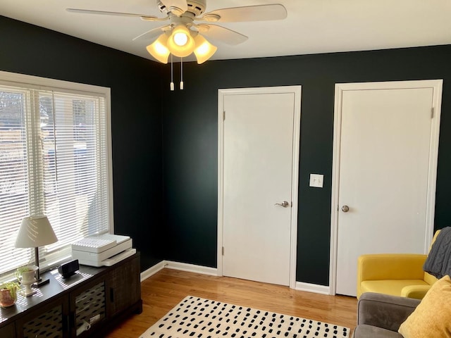 sitting room featuring light wood-type flooring, a wealth of natural light, and baseboards