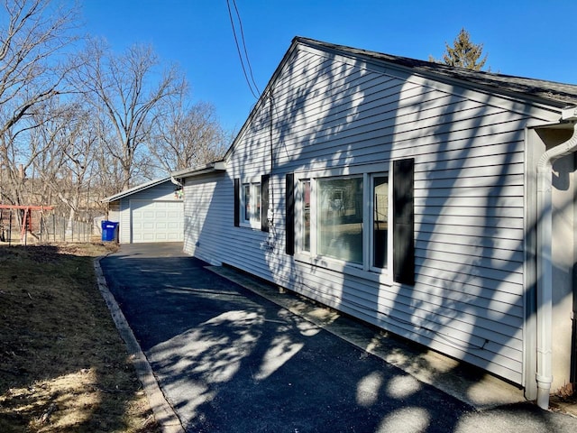 view of side of home with a garage, fence, and an outbuilding