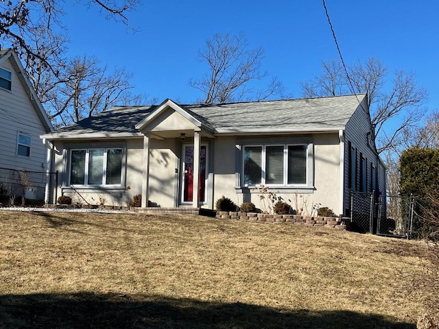 view of front of home featuring a shingled roof, fence, a front lawn, and stucco siding