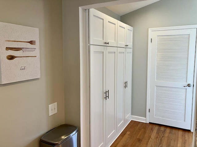 hall with dark wood-style flooring and baseboards