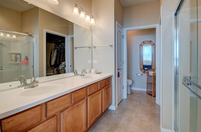 full bathroom featuring double vanity, a shower stall, toilet, and a sink