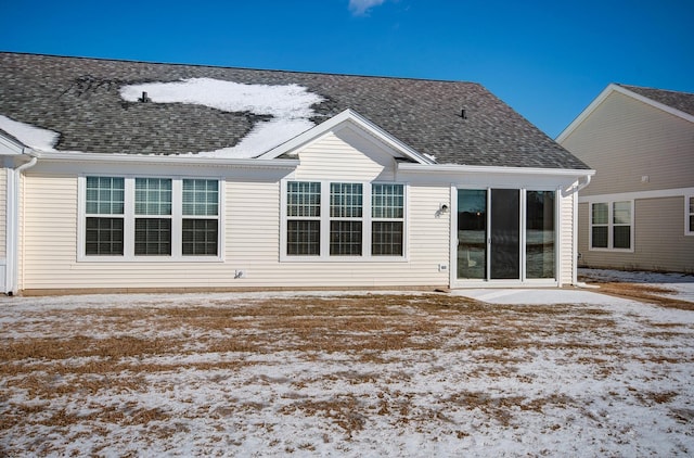 snow covered property with a shingled roof