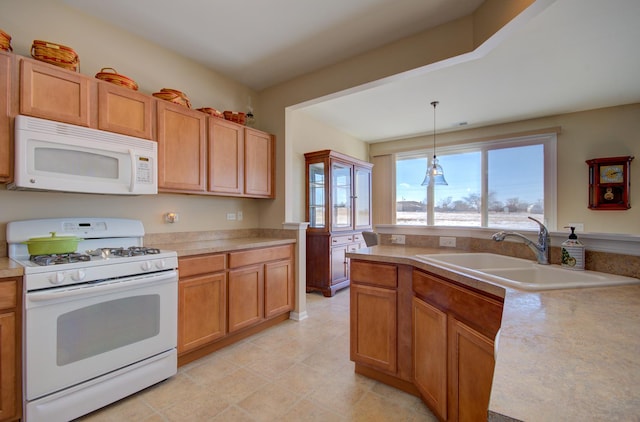 kitchen featuring white appliances, pendant lighting, light countertops, and a sink