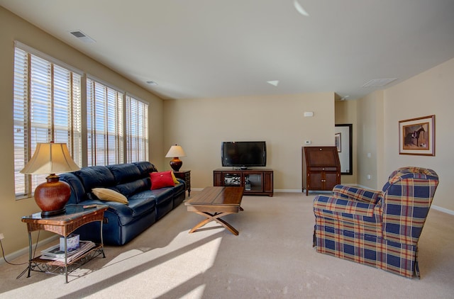 living area featuring baseboards, visible vents, and light carpet