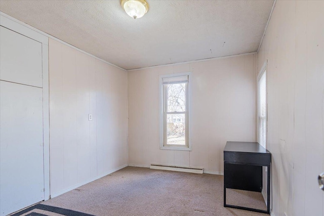 empty room with a textured ceiling, a baseboard heating unit, and carpet flooring