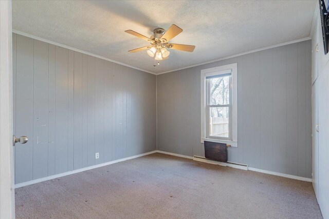 empty room with a ceiling fan, a baseboard radiator, carpet flooring, and crown molding