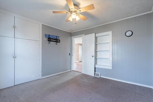 unfurnished bedroom with carpet, visible vents, ornamental molding, and a textured ceiling