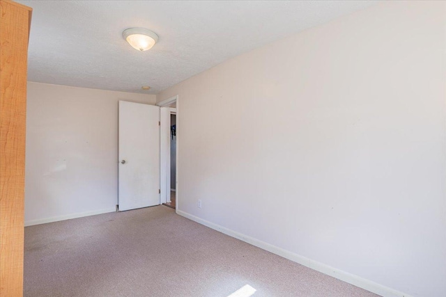 carpeted spare room with a textured ceiling and baseboards