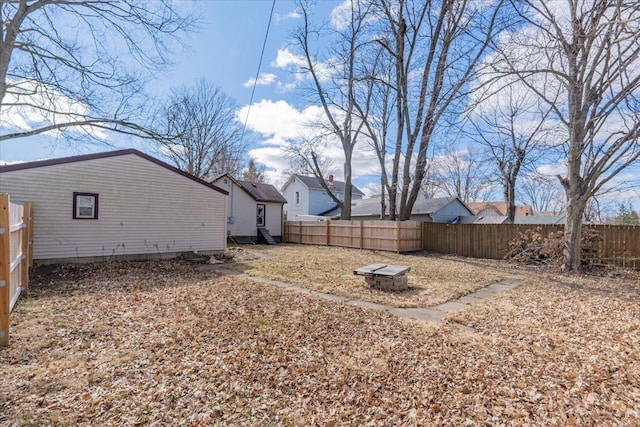 view of yard featuring a fenced backyard and a fire pit