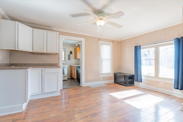 interior space featuring dishwasher, white range oven, ornamental molding, light wood-style floors, and white cabinetry