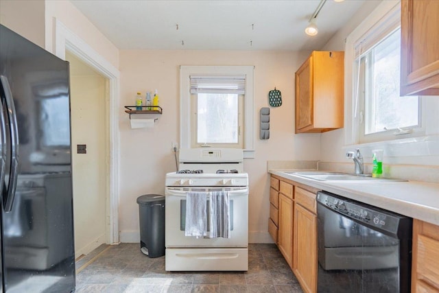 kitchen featuring black appliances, light countertops, a sink, and a wealth of natural light