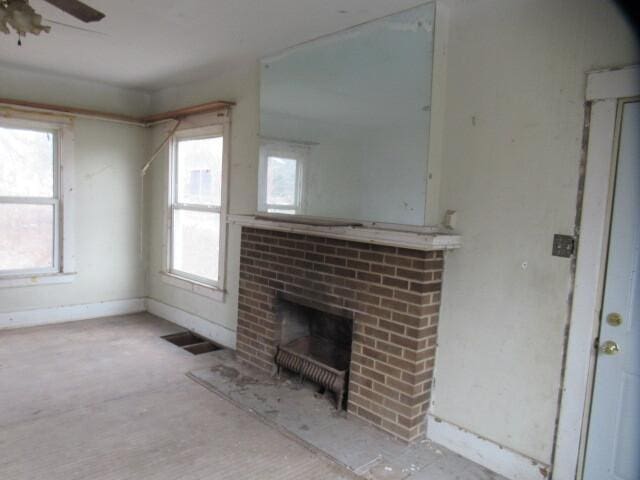 unfurnished living room featuring a brick fireplace, ceiling fan, visible vents, and a wealth of natural light