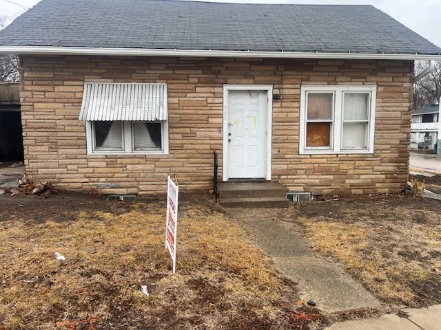 view of front of house featuring stone siding, entry steps, and a shingled roof