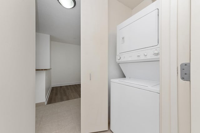 laundry room with baseboards, stacked washer / drying machine, and laundry area
