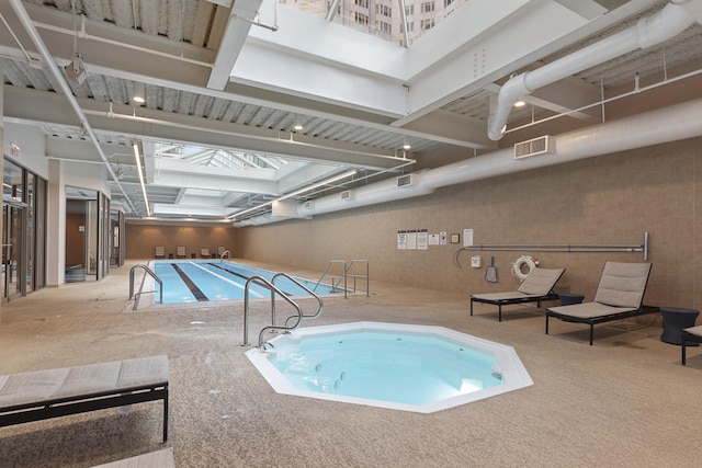 pool with a skylight and an indoor hot tub